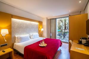 a hotel room with a bed with a red blanket at Abba Rambla Hotel in Barcelona
