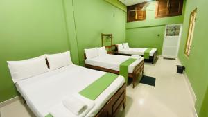 twee bedden in een kamer met groene muren bij Columbus villa in Jaffna