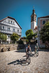 SohlandにあるLandhotel Waldschlößchen mit Gaststubeの時計塔のある通りを自転車で走る3人