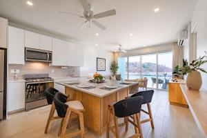 une cuisine avec des placards blancs et une grande île avec des chaises dans l'établissement 3044 - Playa Sur Santa Cruz 301, à Santa Cruz Huatulco