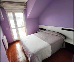a purple bedroom with a bed and a window at ApartamentoDJ in Suances +13 photos