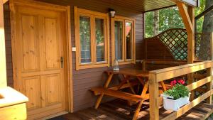 a porch of a cabin with a wooden table and a bench at Letnisko Laba in Pobierowo +11 photos