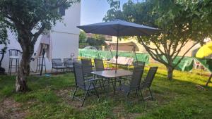 einen Tisch und Stühle mit einem Regenschirm im Gras in der Unterkunft Sogo in Villeneuve-sur-Lot
