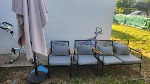 drei Stühle und ein Sonnenschirm neben einem Gebäude in der Unterkunft Sogo in Villeneuve-sur-Lot + 2 Fotos