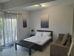 a bedroom with a bed and a couch and a table at Ομορφο νεο στουντιο στην πολη της Ιτεας in Itea