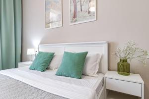 a bedroom with a white bed with green pillows at Tokyo, a Residential Complex in Astana