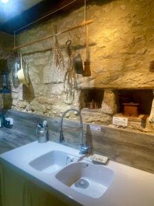 a sink in a kitchen with a stone wall at Les Galineaux in La Roquille