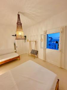 a white room with a bed and a window at Walk The View Apartment with village view in Chora in Ios Chora