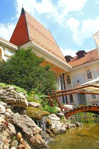 une maison avec un pont sur un ruisseau d'eau dans l'établissement Hotel Prezident, à Palić