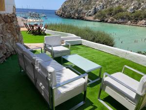 a patio with chairs and a table and a view of the ocean at Menorca Dreams, Acceso Directo a Playa in Cala en Porter +27 photos