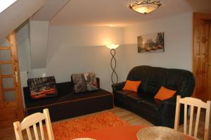 ザラエゲルセグにあるÁlom Kuckó Apartmanのリビングルーム(黒い革張りのソファ、オレンジの枕付)