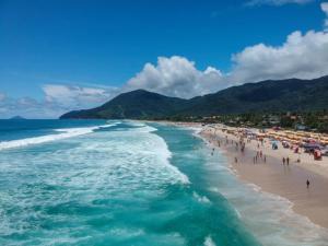 a group of people on a beach with the ocean at Flat Maresias in São Sebastião