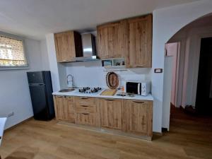 een keuken met houten kasten en een zwarte koelkast bij Domu Mea in Quartu SantʼElena