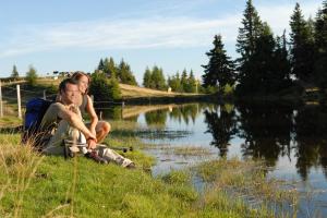 two people sitting on the grass next to a river at Kärnten Card inkludiert - Apartments nahe Bad Kleinkirchheim in Afritz