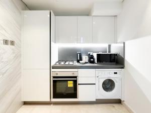a kitchen with white cabinets and a washer and dryer at Trophy - Elevated Living in Luxurious Business Bay Loft in Dubai