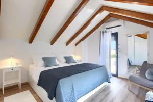 a white bedroom with a blue bed and a chair at House Lando in Pula +24 photos