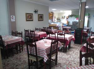 um restaurante com mesas e cadeiras vermelhas e brancas em Hostal Virgen Del Rocío em Ronda