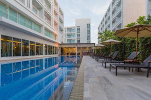 een zwembad met banken en parasols naast een gebouw bij Kantary 304 Hotel Prachinburi in Si Maha Phot