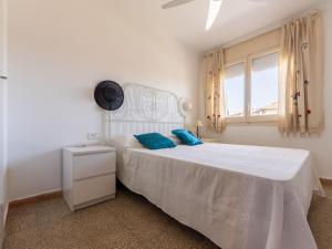 ein weißes Schlafzimmer mit einem weißen Bett und blauen Kissen in der Unterkunft Apartment Cesar by Interhome in Cunit