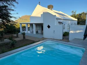 a white house with a swimming pool in front of it at Dream On Cottage in Prince Albert