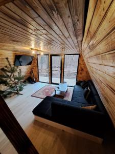 a living room with a black couch and some windows at CabanaAframe in Curtea de Argeş