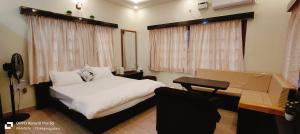 - une chambre avec un lit blanc, un bureau et une fenêtre dans l'établissement NAVARATHNA International resort, à Sollebail