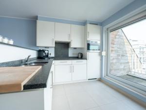 a kitchen with white cabinets and a large window at Apartment Parklane-3 by Interhome in Bredene
