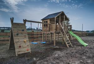 a wooden playground with a slide and a play structure at Lawendowy Zakątek 3 domek z balią in Sominy