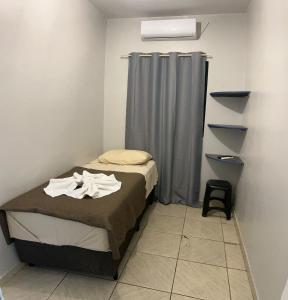 a small bedroom with a bed and a curtain at Cerrado Plaza Hotel -dourados in Dourados