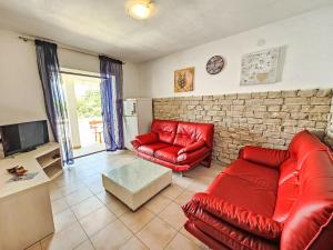 een woonkamer met rode lederen meubels en een bakstenen muur bij Apartment Octopus-5 by Interhome in Bogomolje
