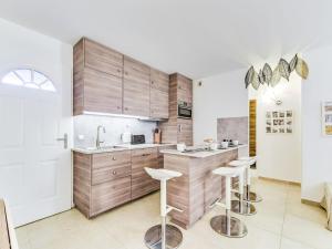 a kitchen with wooden cabinets and stools at Apartment Le Jardin d'Artemis-1 by Interhome in Saint-Tropez +14 photos