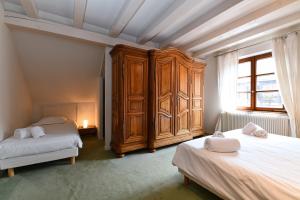 a bedroom with two beds and a large wooden cabinet at Manala - Maison Alsacienne avec Terrasse in Kaysersberg