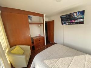 a bedroom with a bed and a chair and a television at Cómodo, céntrico, cerca a Parque Media Luna in Lima