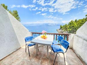 een tafel en stoelen op een balkon met uitzicht op de oceaan bij Apartment Octopus-1 by Interhome in Bogomolje