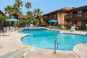 a swimming pool at a resort with chairs and umbrellas at Seagulls Serenade Cozy 1BR Hideaway near Beach 206 in South Padre Island
