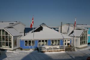 a blue and white building with a flag in the snow at Hotel Icefiord in Ilulissat
