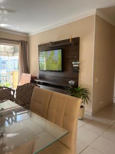 uma sala de estar com um sofá e uma televisão em Lindo apto 3 qtos, a 350 mtrs praia da enseada com serviço de praia e portaria 24 hrs próx casa grande hotel, hipermercados, farmácias bancos no Guarujá