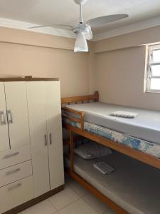 um quarto com dois beliches e um ventilador de teto em Lindo apto 3 qtos, a 350 mtrs praia da enseada com serviço de praia e portaria 24 hrs próx casa grande hotel, hipermercados, farmácias bancos no Guarujá