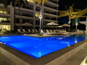 a large pool with chairs and umbrellas in front of a building at Serene Beachfront Escape Includes Delicious Breakfast in Puerto Vallarta