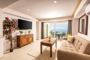 a living room with a couch and a tv and a table at Serene Beachfront Escape Includes Delicious Breakfast in Puerto Vallarta