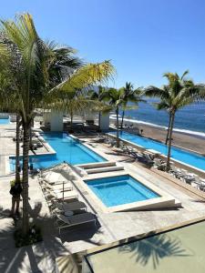 a resort with two pools and chairs and palm trees at Serene Beachfront Escape Includes Delicious Breakfast in Puerto Vallarta