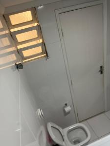 um banheiro com vaso sanitário e janela em Lindo apto 3 qtos, a 350 mtrs praia da enseada com serviço de praia e portaria 24 hrs próx casa grande hotel, hipermercados, farmácias bancos no Guarujá mais 17 fotografias