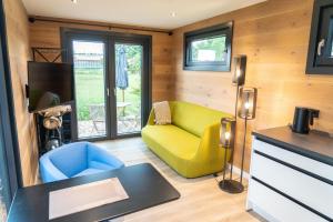 a living room with a yellow chair and a couch at HofGut Bockelkathen Tiny Haus 9 in Lüdersburg
