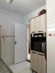 uma cozinha com geladeira e micro-ondas em Lindo apto 3 qtos, a 350 mtrs praia da enseada com serviço de praia e portaria 24 hrs próx casa grande hotel, hipermercados, farmácias bancos no Guarujá