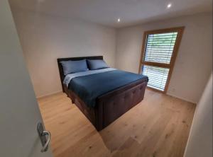 a bedroom with a bed with blue sheets and a window at Maison neuve indépendante louée spécialement pour les vacances in Les Pléiades