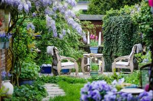 2 sillas y una mesa en un jardín con flores púrpuras en Fisherman's Home, en Vinkeveen
