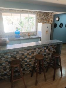 uma cozinha com um balcão com bancos e uma geladeira em Cobertura em Aperibé em Aperibé