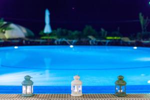 three bottles with lights next to a swimming pool at Kalimera Hotel in Akrotiri