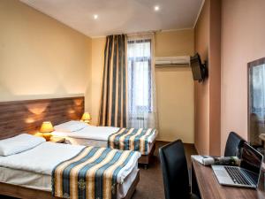 a hotel room with two beds and a laptop on a desk at Lviv Central Jam Hotel in Lviv