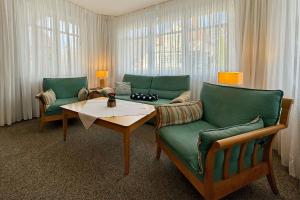 sala de estar con 2 sillas verdes y mesa en Villa Viktoria Whg 1 - "Sandbank", en Kolpinsee